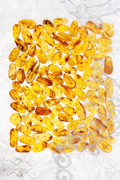 Stones of yellow amber and white lace lie on a flat textured sur — Stock Photo, Image