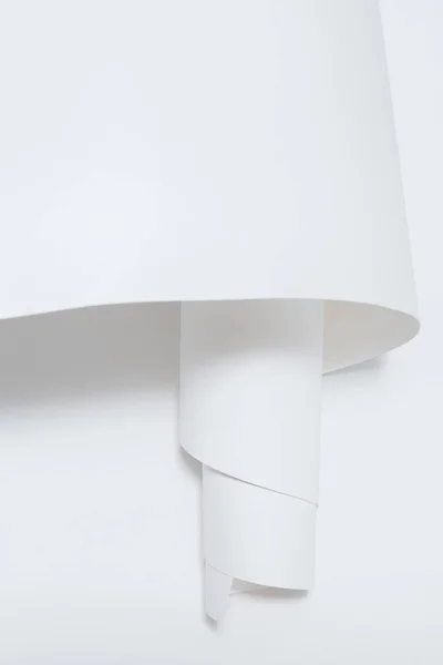 Uma folha enrolada de papel branco sobre um fundo branco . — Fotografia de Stock