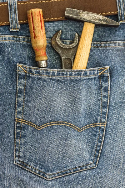 Serie di strumenti vecchi in una tasca posteriore di jeans Immagine Stock