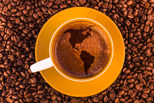 Map of America on fresh espresso with a beautiful crema and strewn mediumly roasted coffee beans