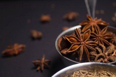 Badian. Star Anice siyah arka planda metal bir kaseye yakın çekim yapıyor. Hint tatlısı pişirmek için. Seçici odaklanma. Yemekler için baharat ve şifalı otlar kullanma kavramı. Tadı güzelleşiyor.