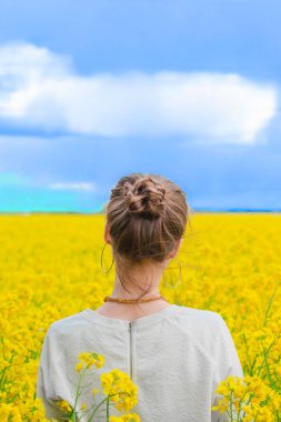  Yaz mevsiminde kolza tohumu tarlasında esmer bir kız mavi gökyüzü arka planında vuruldu. Neşe ve mutluluk dolu kolza tohumu tarlasında mutlu, güzel bir genç kadın. Özgürlük ve çocukluk kavramı 