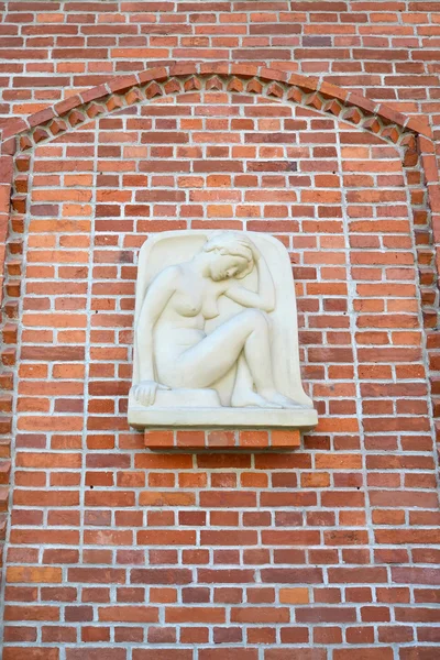 Basrelief "das hockende Mädchen" (Genie) auf einer roten Ziegelwand. Kaliningrad — Stockfoto