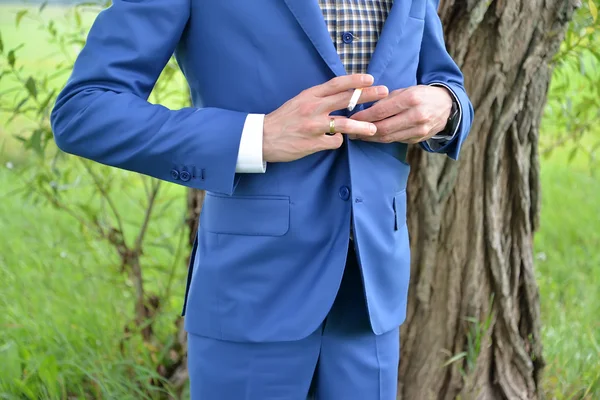 El hombre joven con el cigarrillo en los botones de mano la chaqueta — Foto de Stock