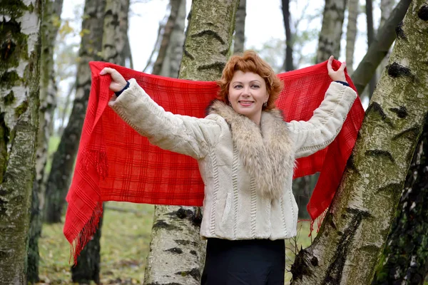 La femme joyeuse des années moyennes tient un étole rouge dans les mains levées — Photo