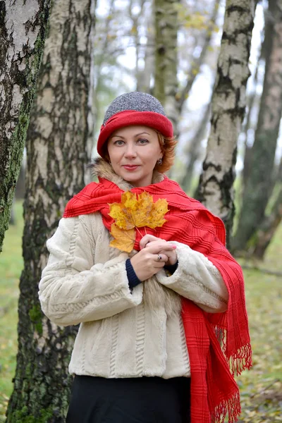 Portrét ženy průměrných letech s žlutým maple listy v rukou — Stock fotografie