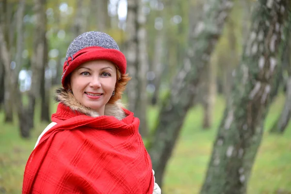 Portrait de la femme joyeuse dans une étole rouge et un chapeau dans un bois de bouleau — Photo