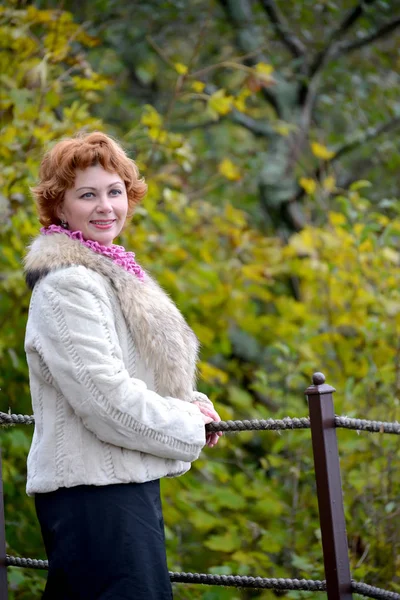 Portrait of the happy woman of average years against the background of autumn trees — Stock Photo, Image