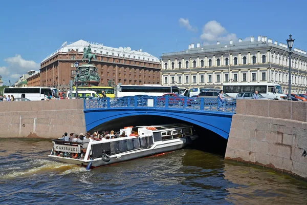 ST. PETERSBURG, RUSIA - 11 DE JULIO DE 2016: El barco de excursión flota bajo el puente azul a través del río Moika — Foto de Stock