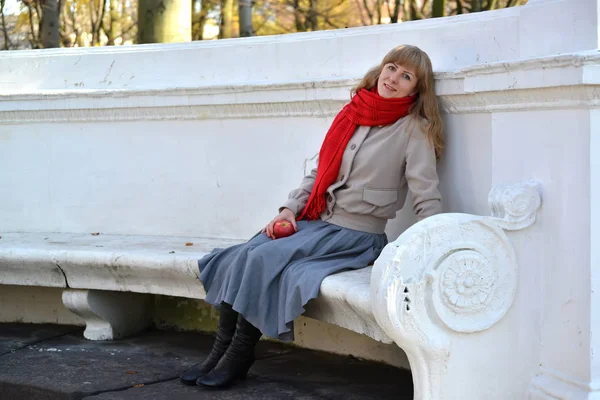 La jeune femme à la pomme rouge à la main s'assoit sur un banc dans le parc — Photo