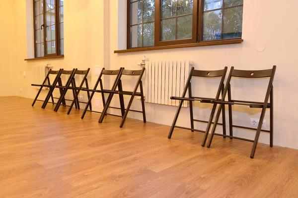 Wooden chairs stand in a row along a wall in the hall. Interior — Stock Photo, Image