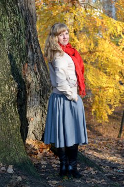 Genç güzel kadın maliyetleri yarı açık-bir sonbahar ağaç arka planı