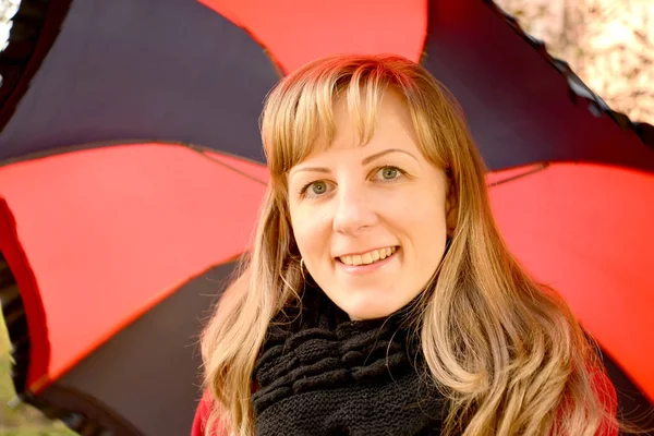 Портрет молодой веселой женщины на фоне черно-красного зонта — стоковое фото