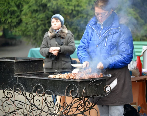 Kaliningrad, Rusland - 13 November 2016: De vrouw een shish kebab op een straat brazier frietjes — Stockfoto