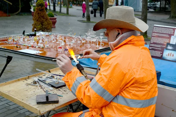 REGIÓN DE KALINININGRAD, RUSIA - 13 DE ABRIL DE 2014: El soplador de vidrio de artista callejero Yury Lenshin trabaja con una antorcha de gas —  Fotos de Stock
