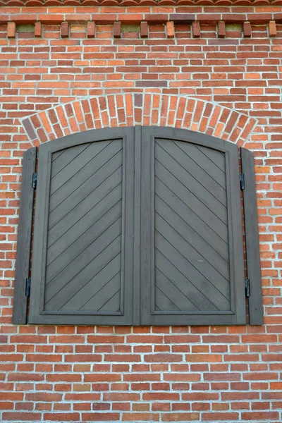 Houten zon blind op een rode bakstenen muur, imitatie van een venster — Stockfoto