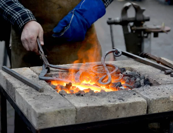 The smith heats until red a metal detail in a forge brazier