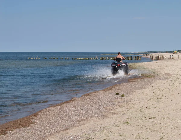 The man goes on the ATV on the coast of the Baltic Sea — Stock Photo, Image