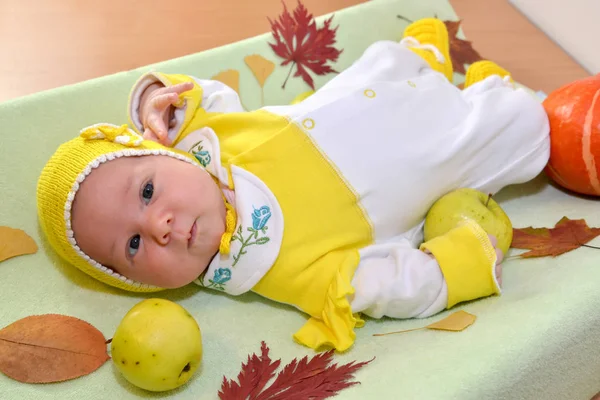 Le bébé repose sur une table parmi les feuilles et les fruits d'automne — Photo