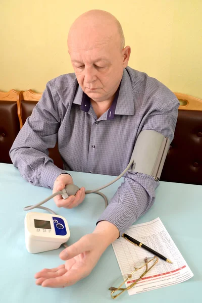 The pensioner measures pressure by an electronic tonometer semiautomatic device