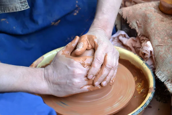 As mãos do homem trabalham com o barro na roda de um oleiro — Fotografia de Stock