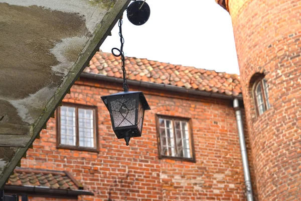 Dekorativní lampa na pozadí cihlovou zeď zámku rytířů. Polsko, Kentshin — Stock fotografie