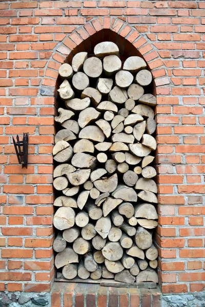 Hranice dřeva palivové dříví je do arch clony cihlová zeď — Stock fotografie