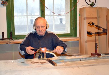 Kentshin, Polonya - 03 Ocak 2014: Erkek cam blower cam hazırlık gaz brülör üzerinde ısıtıyor. Fabrika Noel ağacı süslemeleri