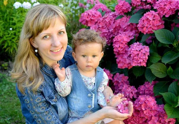 Retrato de la joven con el niño sobre la hortensia floreciente — Foto de Stock