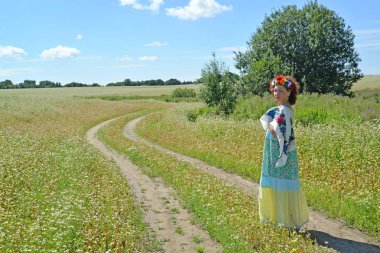 Kafasına bir çelenk kadınla çiçek açması buğday alanında bir yolda gider