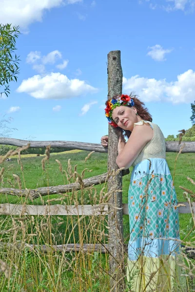 Kafasına bir çelenk ile ortalama yıl kadın bir çit karşı eğildi