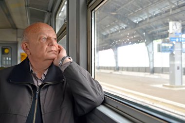 Erkek emekli düşünceli Elektrikli tren pencereden görünüyor