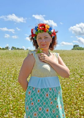 Olgun kadın ile kafasına bir çelenk çiçek buğday alan arka planı tutar.