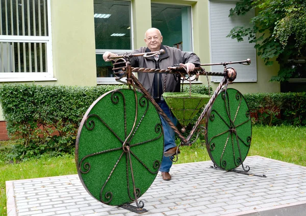 Mannen står nära en topiarny skulptur ”cykel”. Svetlogorsk, — Stockfoto