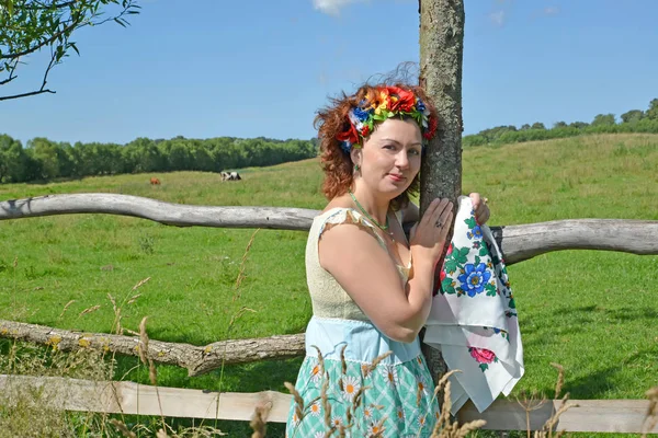 Bir çelenk elinde renkli bir eşarp ve baştan kadınla bir çitin duruyor