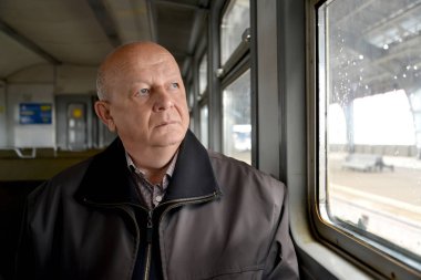 Yaşlı adam düşünceli Elektrikli tren pencereden dışarı bakar
