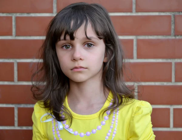 Portrét smutný holčička na pozadí cihlová zeď — Stock fotografie