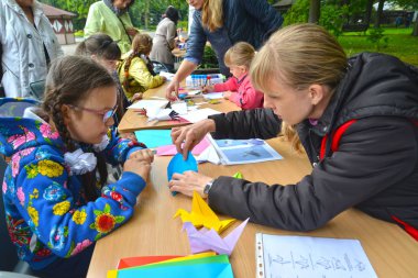 Kaliningrad, Rusya Federasyonu - 17 Eylül 2017: Genç kadın origami koymak için kız öğretir. Açık havada çocuk ana sınıfı
