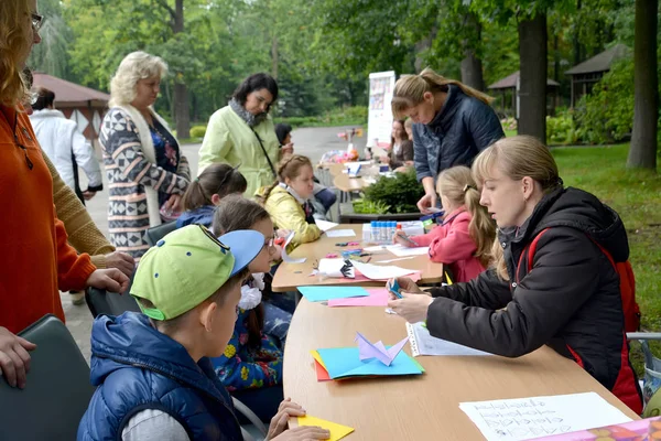 КАЛИНИНГРАД, РОССИЯ - 17 СЕНТЯБРЯ 2017: Учитель учит детей класть оригами. Детский мастер-класс на открытом воздухе — стоковое фото