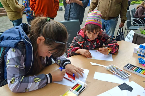 КАЛИНИНГРАД, РОССИЯ - 17 СЕНТЯБРЯ 2017 г.: Дети рисуют детали бумажного самодельного изделия. Детский мастер-класс на открытом воздухе — стоковое фото