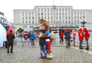 KALININGRAD, RUSSIA - OCTOBER 14, 2017: A mascot of the FIFA World Cup of FIFA 2018 Zabivaka wolf embraces the girl clipart