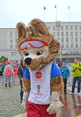 KALININGRAD, RUSSIA - OCTOBER 14, 2017: A mascot of the FIFA World Cup of FIFA 2018 Zabivaka wolf against the background of the City Hall clipart