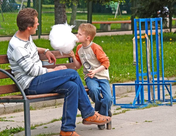 ST. PETERSBURG, RUSIA - 06 DE JUNIO DE 2008: El padre con el hijo come algodón de azúcar en un banco del parque — Foto de Stock