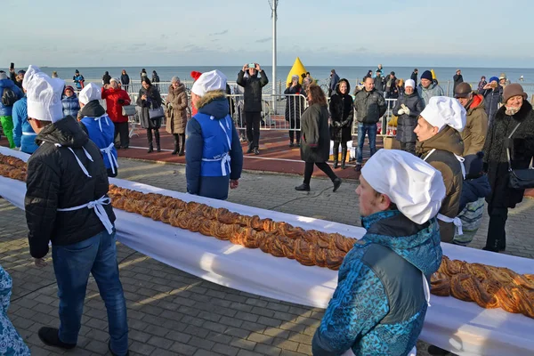 ЗЕЛЕНОГРАДСК, РОССИЯ - 13 ЯНВАРЯ 2018: Мужские пекари несут сладкий пирог длиной 18 метров на набережной. Фестиваль Кранцевского пирога — стоковое фото