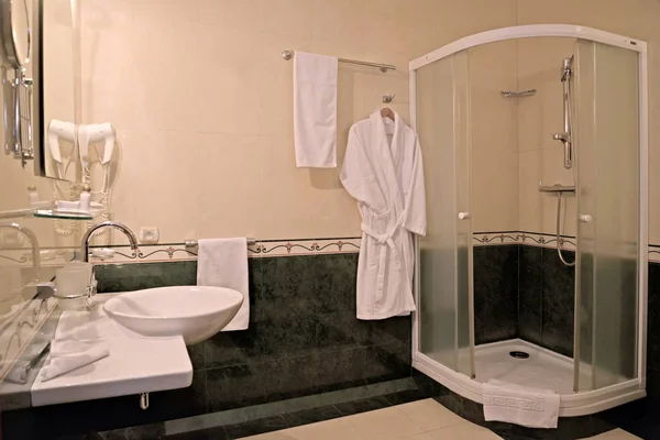 Toalettinteriør med dusjbås og badekåpe – stockfoto