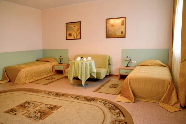 Interior de un dormitorio con dos camas y un sofá en colores cálidos —  Fotos de Stock