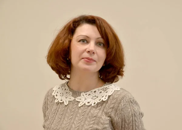 Die Frau im grauen Pullover mit Spitzenkragen. ein Porträt auf hellem Hintergrund — Stockfoto