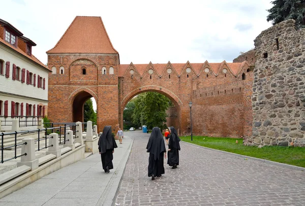 托伦（英语：Torun, Poland）- 2018年8月25日：天主教修女穿过旧城。 14世纪的Gdanisco塔 — 图库照片
