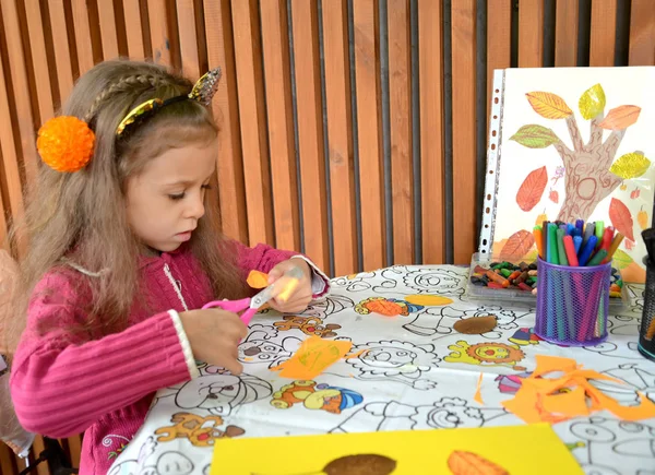 La fille découpe une partie en papier avec des ciseaux pour l'application. Classe de maître extérieure pour enfants — Photo