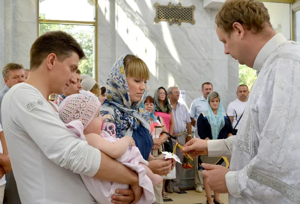 Kaliningrad, Rusland - 04 augustus 2013: Een orthodoxe priester steekt een kaars aan in de handen van een peetmoeder. Doopritueel — Stockfoto